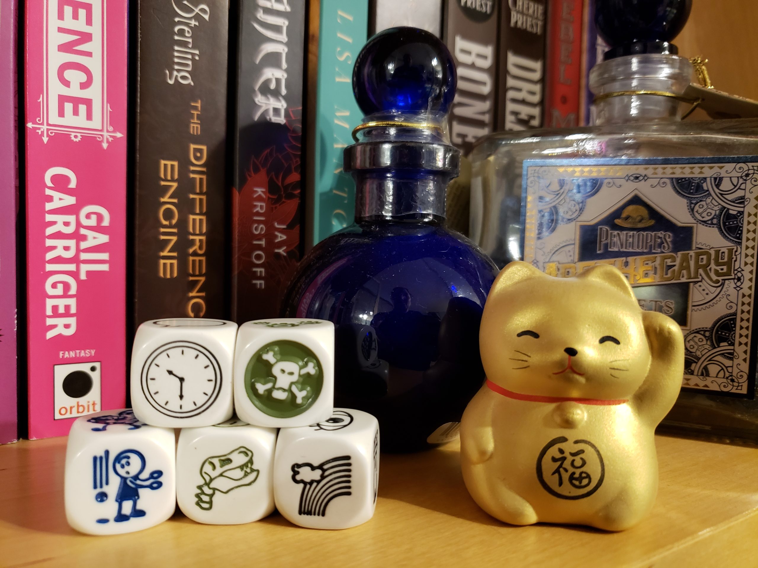 Five of Rory's Story Cubes displaying pictures of a clock, a skull and crossbones, an object falling beside a person, a dinosaur skeleton, and a rainbow.