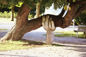 A sculpture of a hand supporting a tree that is growing lopsided, much in the way that you need to support your writing goals using whatever props you can.