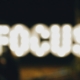 A slightly out of focus image of the word focus spelled in lights, like a writer grasping for focus as they try writing with distractions.